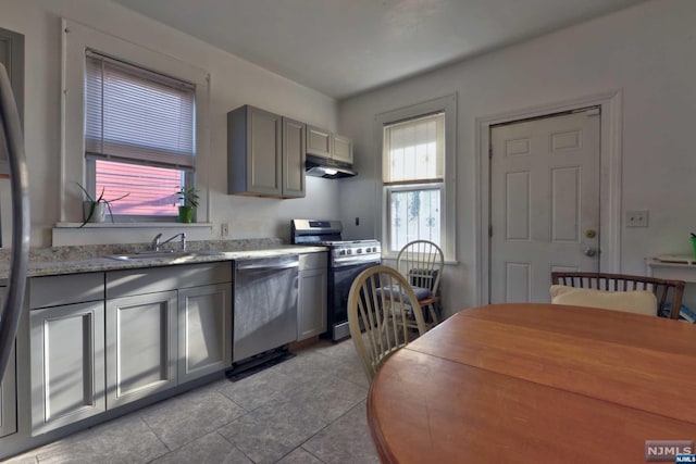 kitchen featuring light stone countertops, appliances with stainless steel finishes, sink, gray cabinets, and light tile patterned flooring