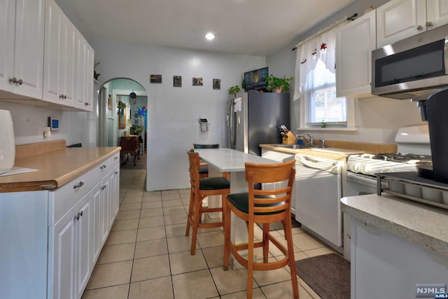 kitchen featuring white cabinets, sink, stainless steel appliances, and light tile patterned flooring