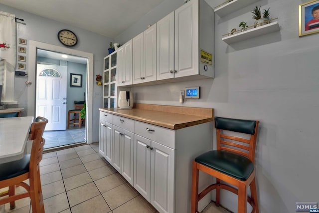 kitchen with butcher block counters, white cabinetry, and light tile patterned floors