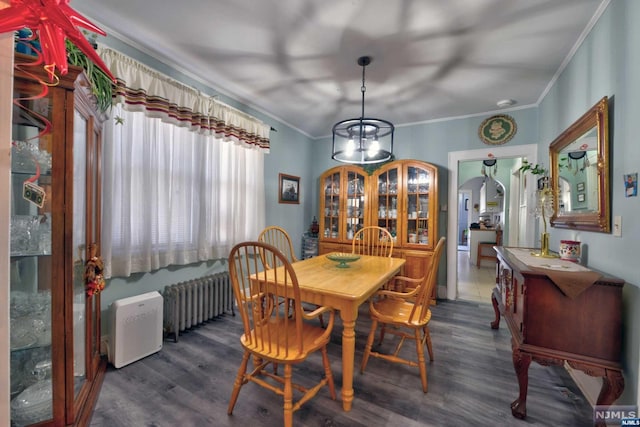 dining room featuring radiator, crown molding, dark hardwood / wood-style flooring, and a chandelier