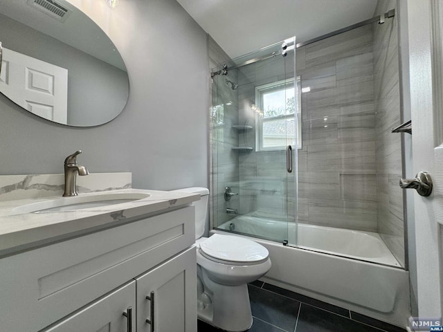 full bathroom with tile patterned flooring, vanity, toilet, and bath / shower combo with glass door