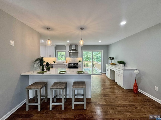 kitchen with white cabinets, wall chimney exhaust hood, pendant lighting, and stainless steel gas range