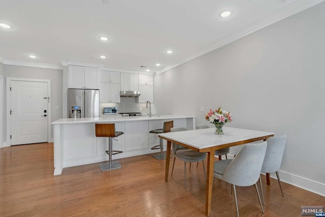 dining area featuring crown molding, sink, and light wood-type flooring