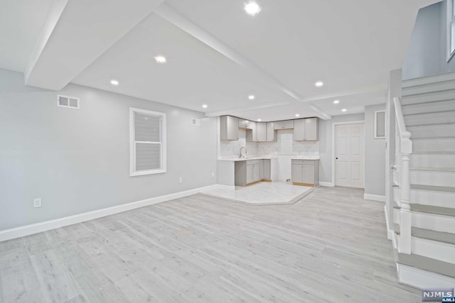 unfurnished living room featuring sink and light hardwood / wood-style flooring