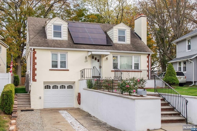 cape cod house featuring solar panels and a garage