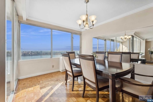 dining room with a water view, baseboards, a chandelier, and ornamental molding