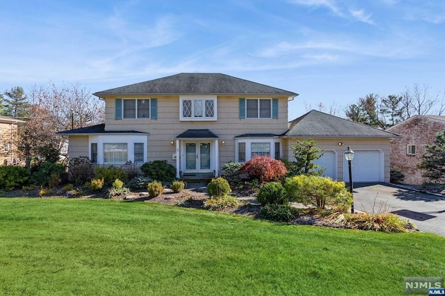 view of front of house with a front yard, french doors, a garage, and driveway