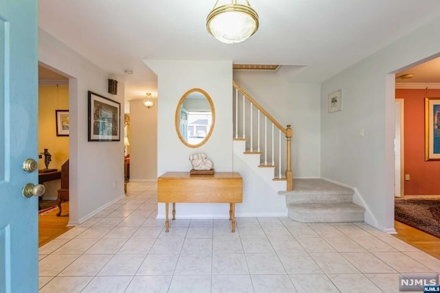 entrance foyer with stairs, light tile patterned flooring, and baseboards