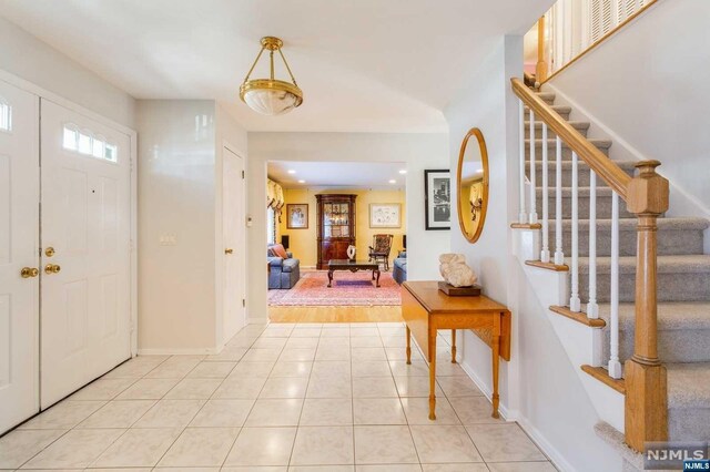 entrance foyer with recessed lighting, baseboards, light tile patterned flooring, and stairs