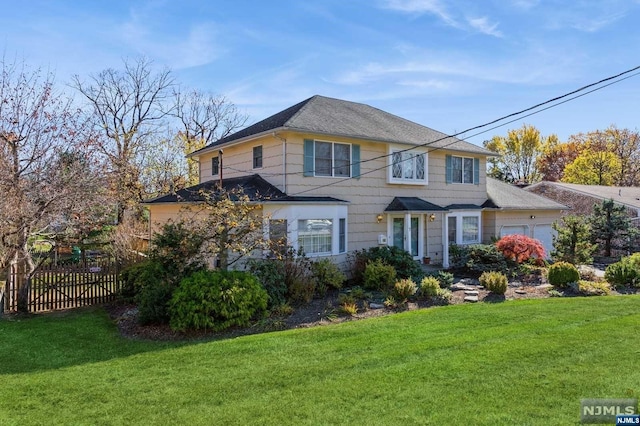 view of front facade featuring a garage, a front lawn, and fence