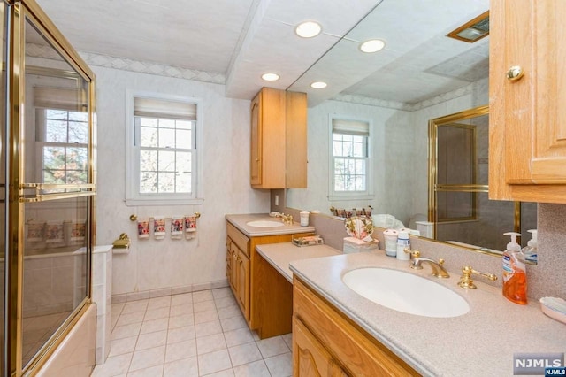 bathroom featuring tile patterned flooring, enclosed tub / shower combo, two vanities, and a sink