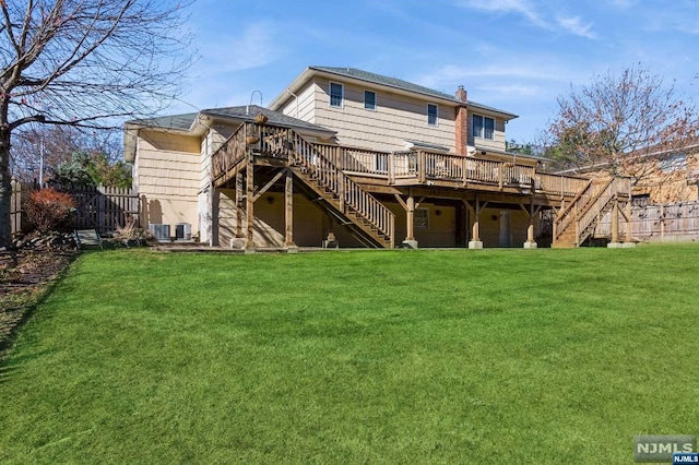 rear view of property featuring fence, a chimney, stairs, a deck, and a lawn