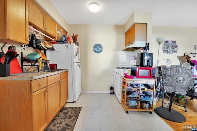 kitchen featuring light tile patterned floors, white appliances, and backsplash