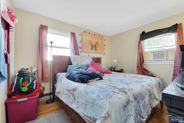 bedroom featuring dark hardwood / wood-style flooring, multiple windows, and cooling unit