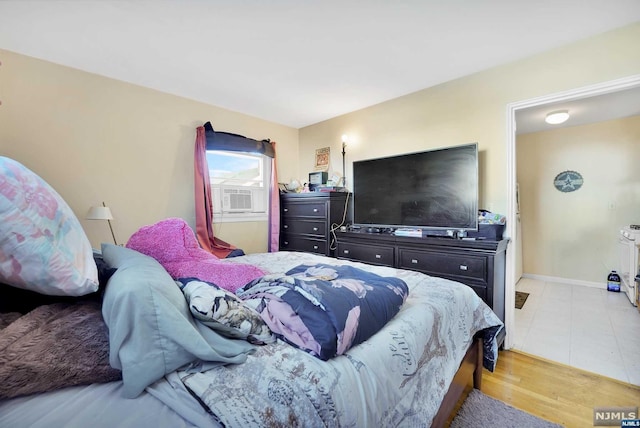 bedroom with cooling unit and light wood-type flooring