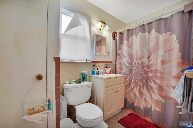 bathroom with vanity, tile walls, and toilet