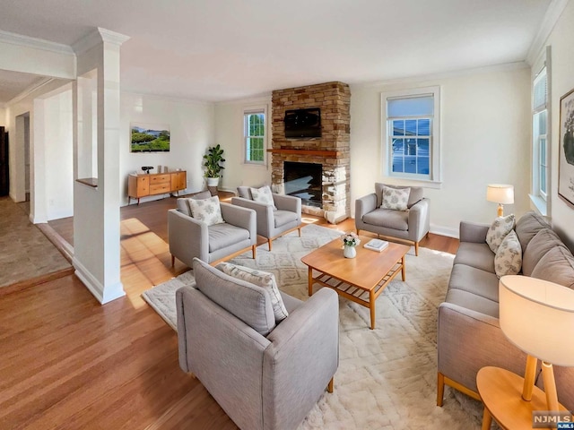 living room featuring a stone fireplace, crown molding, and light hardwood / wood-style flooring