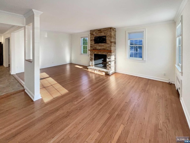 unfurnished living room with a stone fireplace, crown molding, and hardwood / wood-style floors