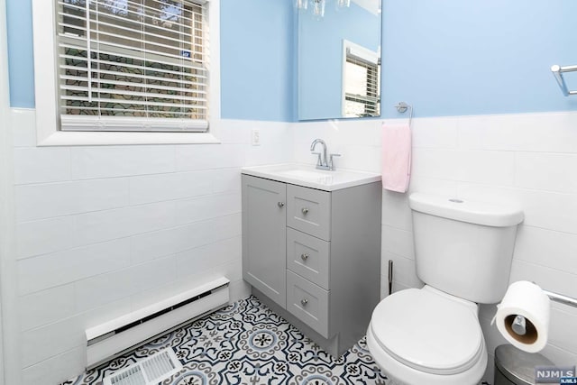 bathroom with a healthy amount of sunlight, toilet, tile walls, and a baseboard radiator