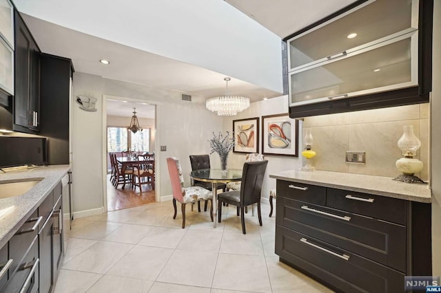 dining area with light tile patterned floors, sink, and an inviting chandelier