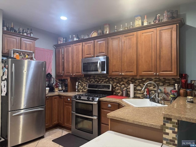 kitchen featuring appliances with stainless steel finishes, backsplash, light tile patterned floors, and sink