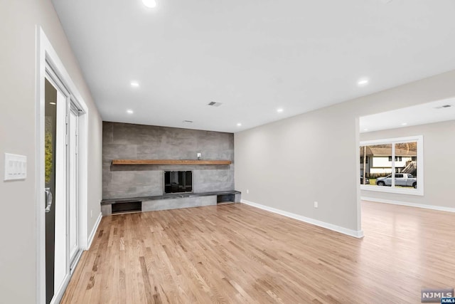 unfurnished living room featuring a large fireplace and light hardwood / wood-style floors