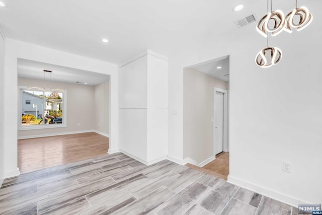 spare room with light wood-type flooring and a notable chandelier