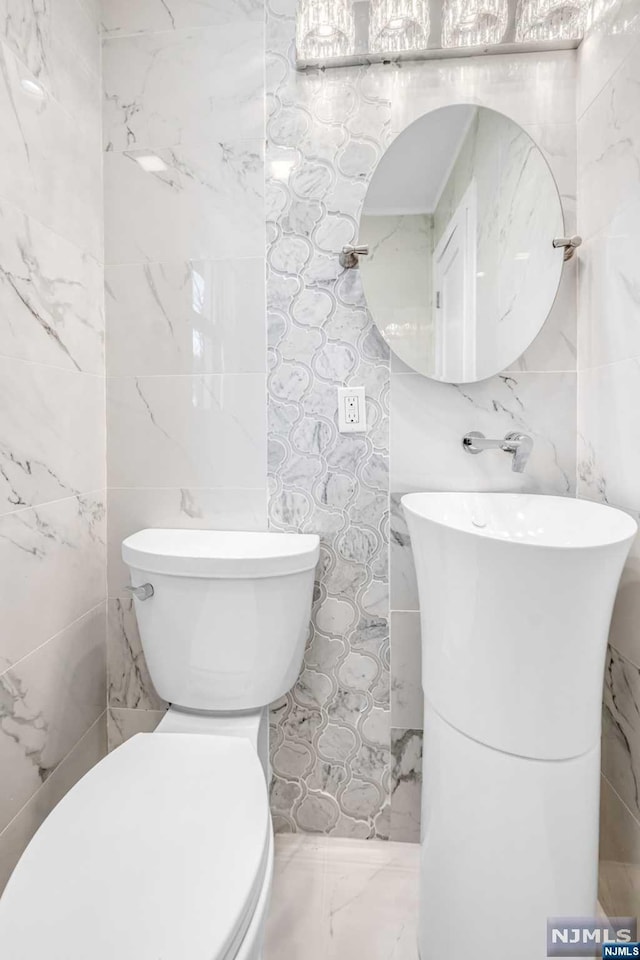 bathroom featuring tile walls and toilet