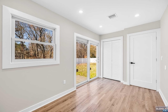 unfurnished bedroom featuring access to outside, a closet, and light hardwood / wood-style flooring