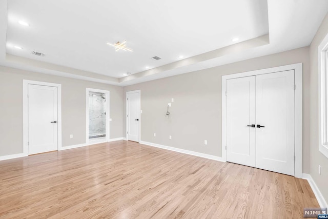 spare room featuring light hardwood / wood-style floors and a raised ceiling