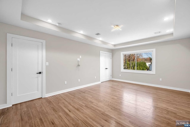 empty room with a tray ceiling and hardwood / wood-style floors