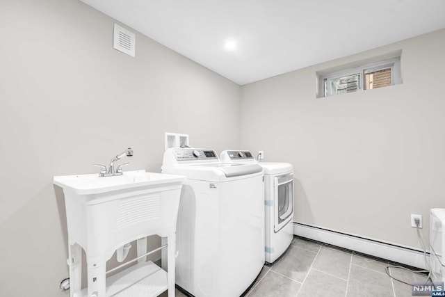 washroom featuring separate washer and dryer, sink, light tile patterned floors, and a baseboard radiator