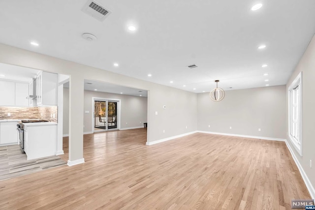 unfurnished living room with a chandelier and light wood-type flooring