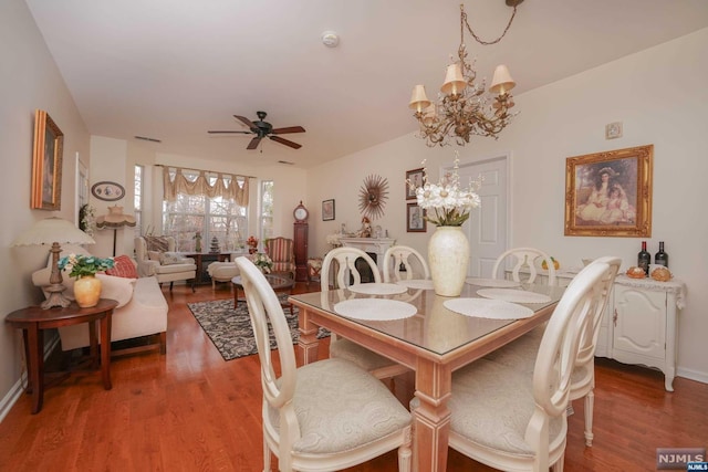 dining space featuring ceiling fan with notable chandelier and wood-type flooring