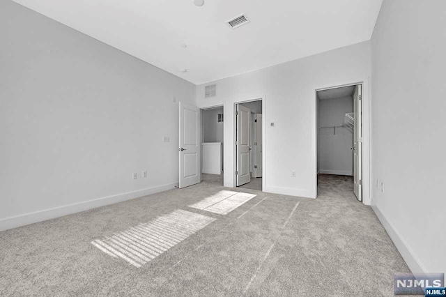 unfurnished bedroom featuring light carpet, a spacious closet, and a closet