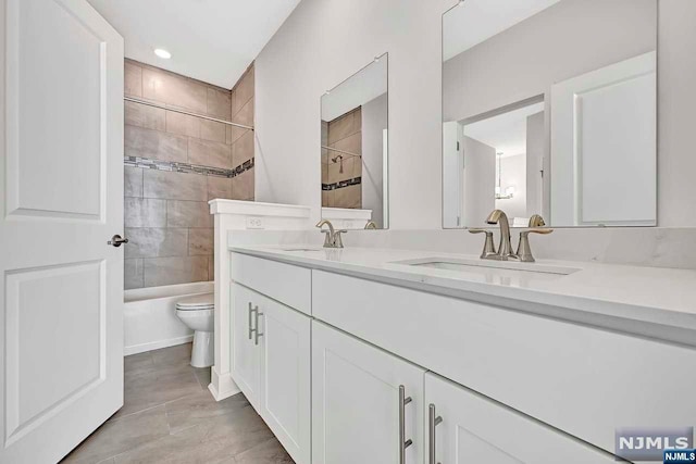 full bathroom featuring tile patterned floors, vanity, toilet, and tiled shower / bath combo