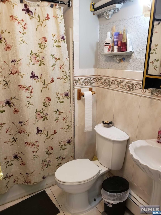 bathroom featuring tile patterned flooring, toilet, baseboard heating, tile walls, and walk in shower