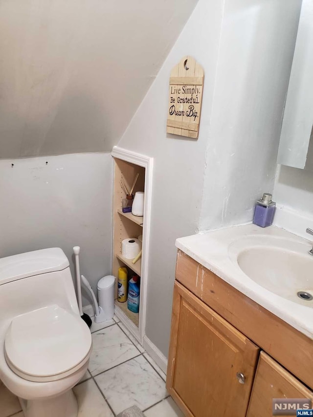 bathroom with vanity, toilet, and lofted ceiling