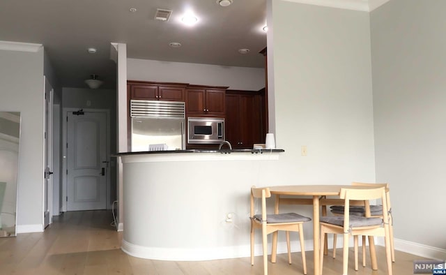 kitchen featuring kitchen peninsula, appliances with stainless steel finishes, and light hardwood / wood-style floors