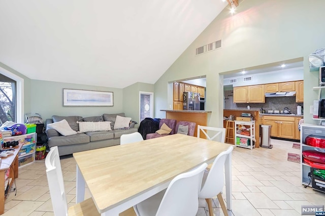 tiled dining room with high vaulted ceiling