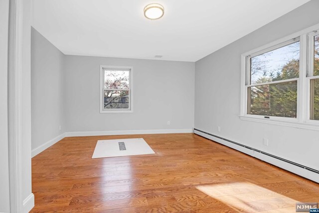 spare room featuring light wood-type flooring and a baseboard heating unit