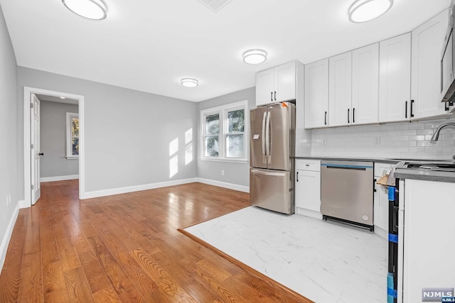 kitchen featuring backsplash, sink, light hardwood / wood-style flooring, appliances with stainless steel finishes, and white cabinetry