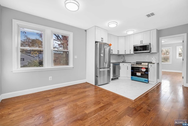 kitchen featuring a wealth of natural light, white cabinetry, light hardwood / wood-style flooring, and appliances with stainless steel finishes