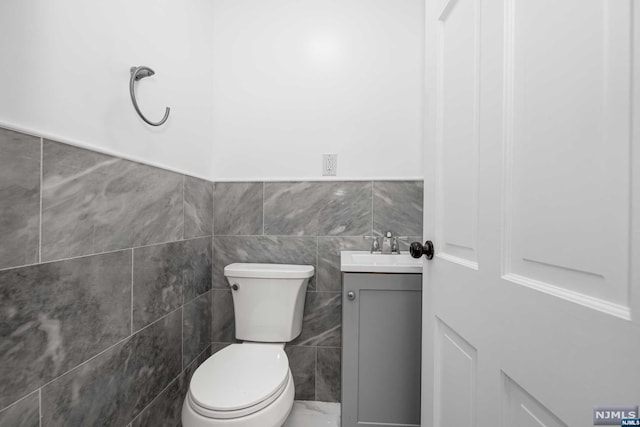 bathroom featuring vanity, tile walls, and toilet