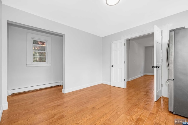 empty room featuring light hardwood / wood-style floors and a baseboard heating unit