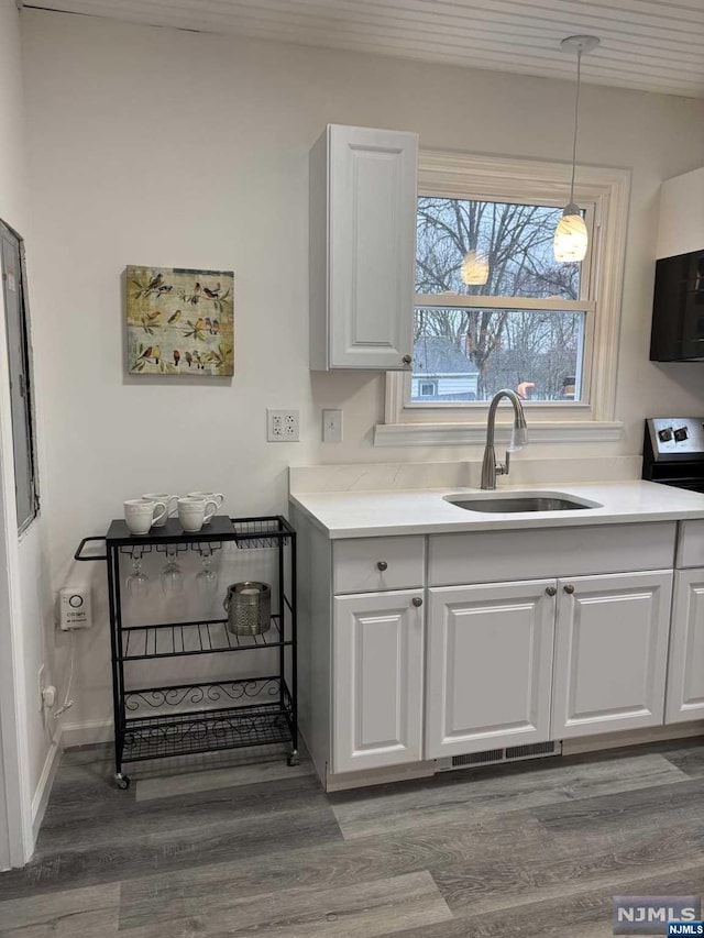 kitchen with white cabinets, sink, hanging light fixtures, dark hardwood / wood-style floors, and range