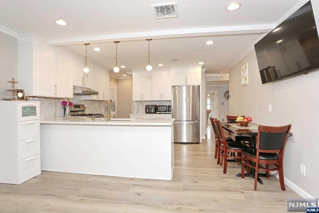 kitchen with white cabinetry, kitchen peninsula, decorative light fixtures, decorative backsplash, and appliances with stainless steel finishes