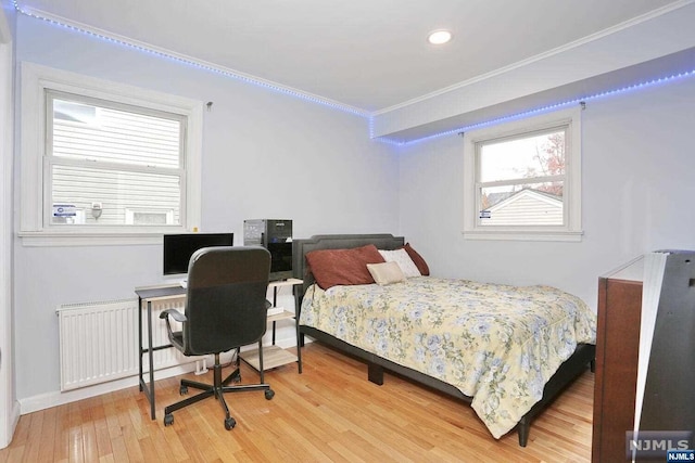 bedroom with radiator heating unit, hardwood / wood-style flooring, and crown molding