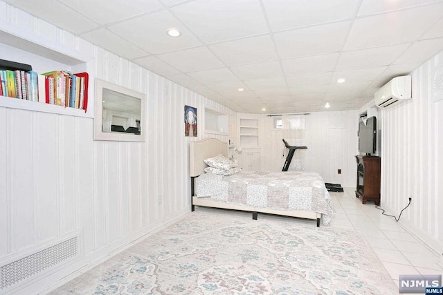 bedroom with a paneled ceiling, light tile patterned floors, and a wall mounted AC