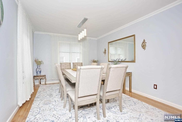 dining room featuring crown molding, an inviting chandelier, and light wood-type flooring